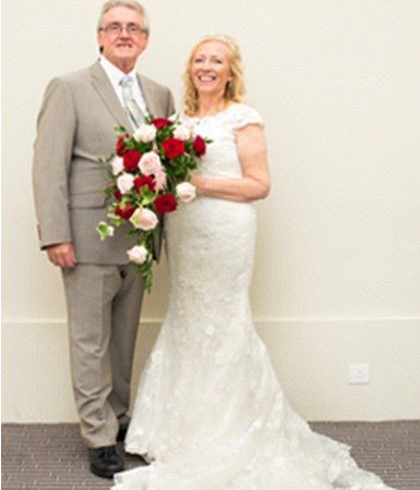 Hilary and Mick Smith happily pose with a bouquet of flowers at their wedding.