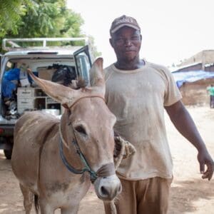 Owner and grey donkey standing outside of mobile clinic