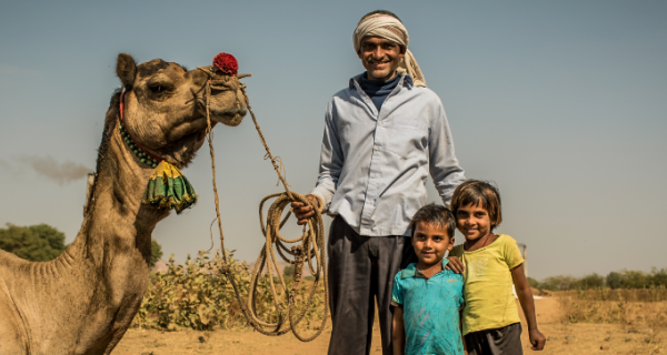 Man and children holding a camel
